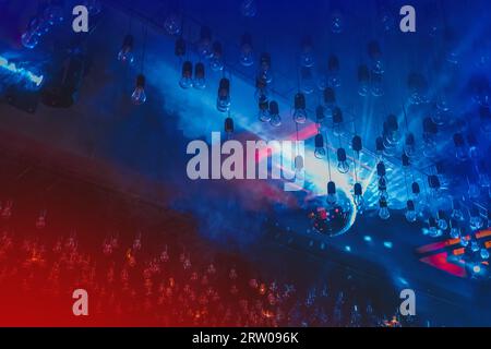 Nightclub atmosphere, ceiling, interior with neon, red and blue light in smoke with disco shiny ball. Stock Photo