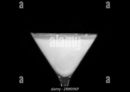 A martini glass with a white alcoholic beverage on an black background, close up. Stock Photo