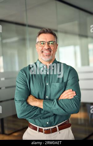 Happy older mature business man executive standing in office, vertical portrait. Stock Photo