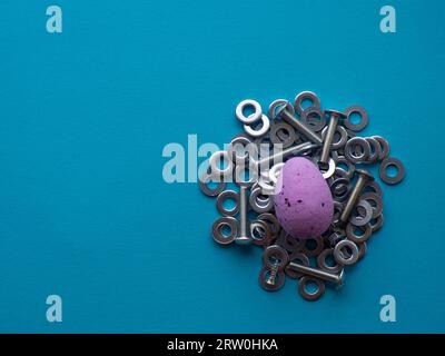 Violet Easter egg on blue background with metal screws Stock Photo