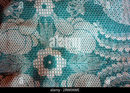 Cotton fabric, fabric of dense green and white threads. Beautiful authentic Ukrainian pattern on fabric of flowers and long leaves, petals. Stock Photo