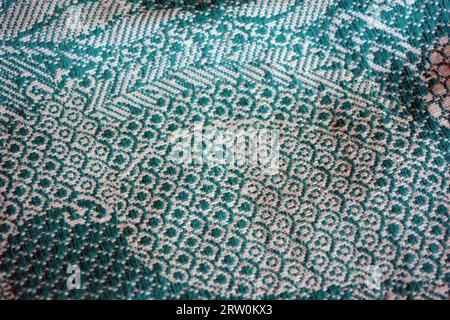 Cotton fabric, fabric of dense green and white threads. Beautiful authentic Ukrainian pattern on fabric of flowers and long leaves, petals. Stock Photo