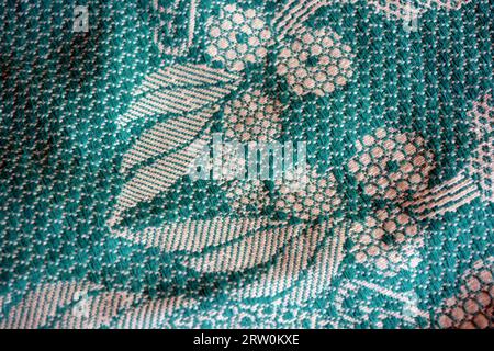 Cotton fabric, fabric of dense green and white threads. Beautiful authentic Ukrainian pattern on fabric of flowers and long leaves, petals. Stock Photo