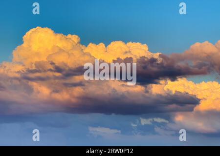Clouds (cumulus) are illuminated by the setting sun with warm coloured light, Germany Stock Photo