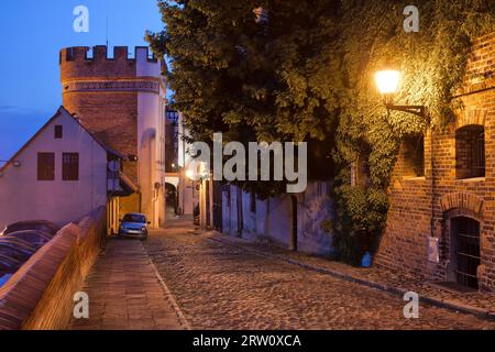 Podmurna street by night and Bridge Gate tower in medieval city of Torun, Poland Stock Photo