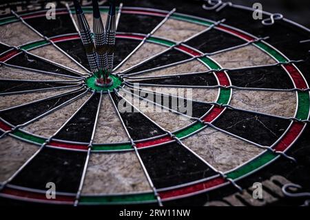 Three dart arrows hitting in the target center of dartboard illustrating the achievement of goals Stock Photo