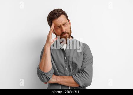 Man feeling sick, touching head and grimacing from painful headache standing on white background Stock Photo