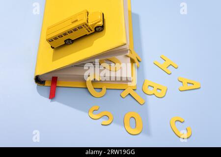A yellow school bus drives over a book with large letters back to school. concept photo. High quality photo Stock Photo