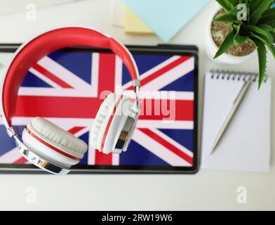 Tablet with image of British flag with headphones and notebook with pen lie on table Stock Photo