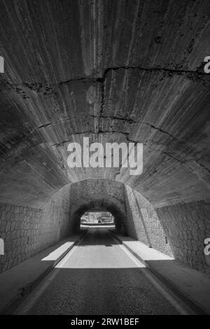 A concrete and stone tunnel under a highway Stock Photo