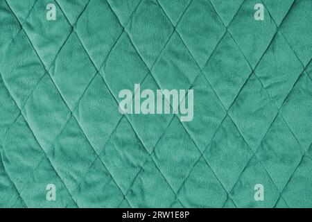 Quilted velours fabric background. Green texture blanket or puffer jacket, stiched with diamond pattern, soft wrinkled surface, crupmed textile Stock Photo