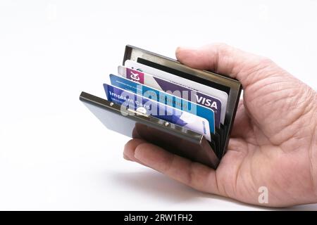 Mans hand holding open Metal credit card case, protector ideal to avoid fraudsters Stock Photo