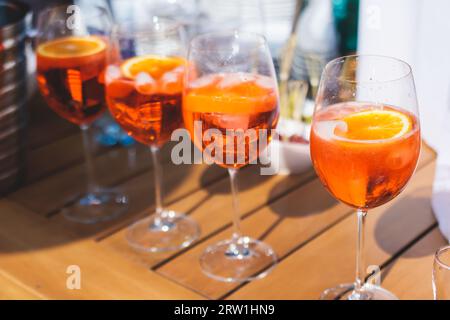 View of alcohol setting on catering banquet table, row line of orange red colored aperitif alcohol cocktails on a party, negroni, spritz and others on Stock Photo