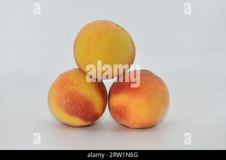 Peaches stacked in three on a white background. Stock Photo