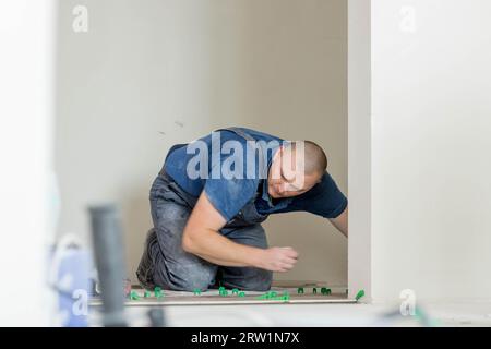 Tiler placing ceramic wall tile in position over adhesive with lash tile leveling system. Ceramic Tiles Stock Photo