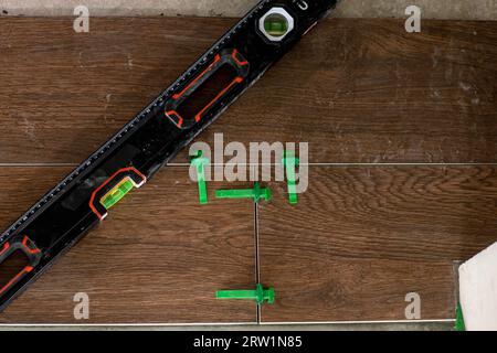 Tile levelling system, four plastic green clips with wedges. Close-up view, selective focus, blurred background. Stock Photo