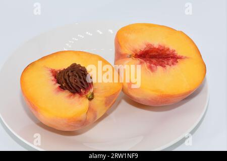 Fresh peaches sliced open on a plate. Stock Photo
