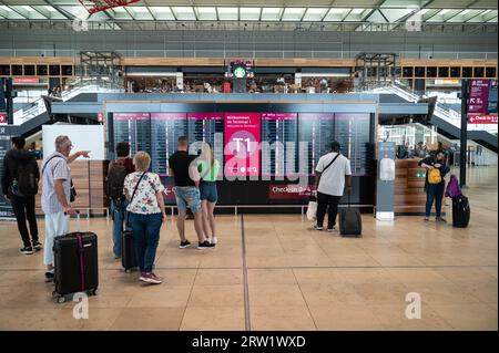 04.06.2023, Germany, Berlin, Berlin - Europe - An interior shot shows air travellers in front of a display board with departures in Terminal 1 of the Stock Photo