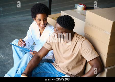 African American woman manager communicates with guy on cargo cart Stock Photo