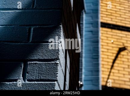 Shapes and shadows around a blue brick wall Stock Photo