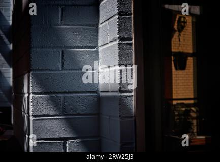 Shapes and shadows around a blue brick wall Stock Photo