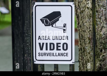 Area Under Video Surveillance Warning sign with picture illustration of camera mount on the wall, black writing on white background Stock Photo