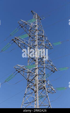 High pylon of a power line against the blue sky Stock Photo
