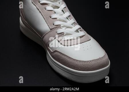 White sneakers with classic lacing on a black background. Stock Photo
