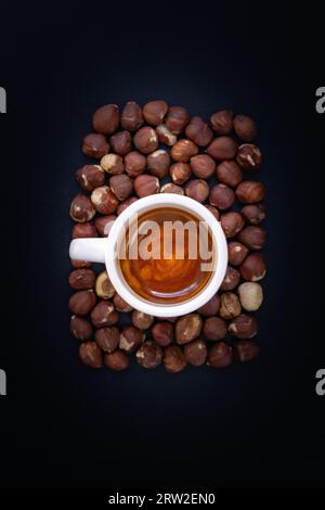 Coffee Espresso In White Cup On Black Slate Background and hazelnuts Stock Photo