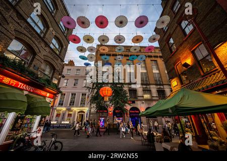 London, UK: Junction of Gerard Street and Macclesfield Street in London's Chinatown. Red Chinese lanterns and colorful parasols hang above the street. Stock Photo
