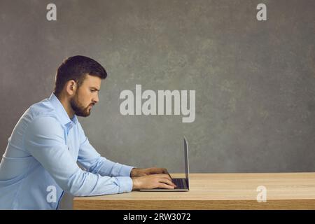 Serious focused smart programmer or employee working with laptop on deadline project. Stock Photo