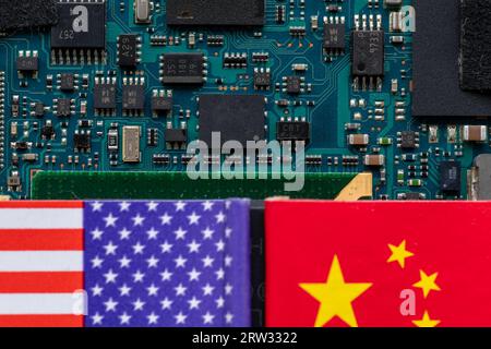 A technology conflict, competition concept with the American and Chinese flags on top of a semiconductor circuit board. Stock Photo