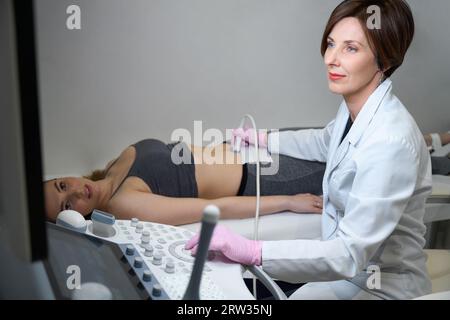 Doctor performs procedure of ultrasound of fetus of pregnant female Stock Photo