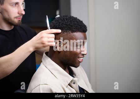 Hairdresser picks up an African American hairstyle for a man Stock Photo