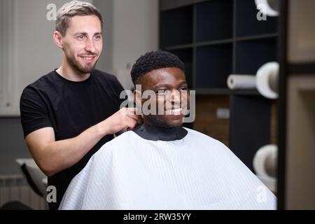 Barber puts on African American protective veil for a client Stock Photo