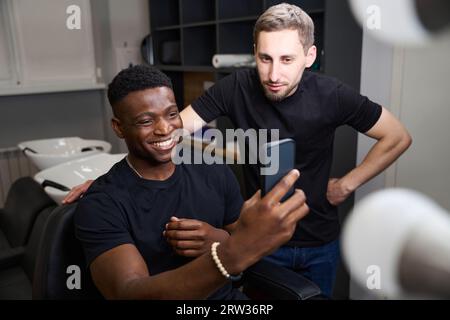Smiling African American guy taking selfie in barbershop Stock Photo
