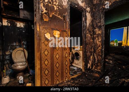 Burnt house interior. Fused remains of furniture and washing machine. Stock Photo