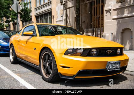 New York City, USA - August 05, 2023: 2011 Ford Mustang V6 yellow car front and passenger side view, parked Stock Photo