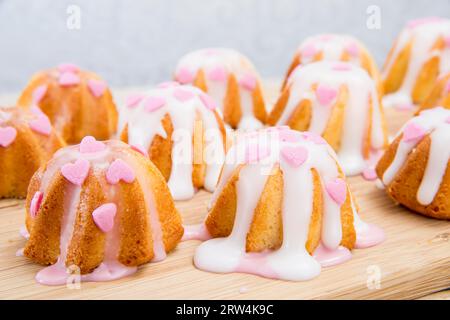 Small sponge cake glazed with icing and sprinkled hearts Stock Photo