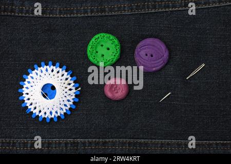 White star thread, buttons, made from modelling clay and a needle, background dark blue denim fabric Stock Photo