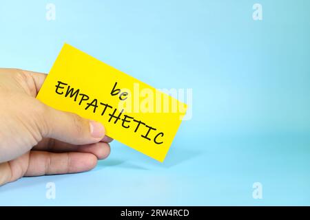 Show empathy reminder concept. Hand holding a bright paper message note. Stock Photo