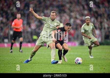 One-on-one Harry Kane FC Bayern Munich FCB (09) vs Granit Xhaka Bayer 04 Leverkusen (34) propped up behind Referee Daniel Schlager Serge Gnabry FC Stock Photo