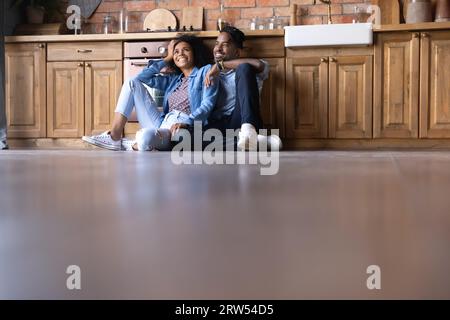 Happy dreamy African American couple sitting on kitchen floor Stock Photo