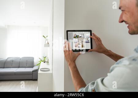 automation, security and technology concept - close up of male hands with video surveillance on tablet pc computer at smart home Stock Photo