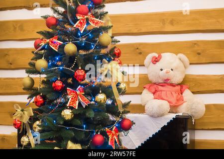 New Year's Christmas holiday green tree decorated toys balloons ribbons on wooden background white soft toy bear. Stock Photo