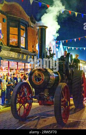 Steam engine trundles in motion blowing steam in evening carnival procession. Ringwood, Hampshire, UK, 16th September 2023. Stock Photo