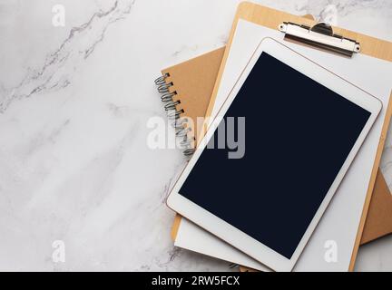 Tablet empty black screen and notebooks  on the office desk Stock Photo