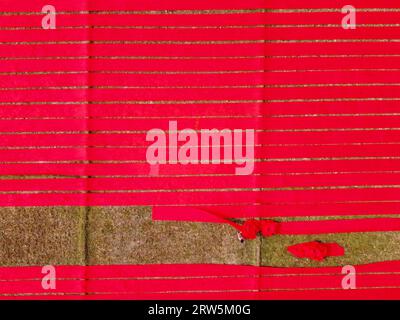 Narsingdi, Bangladesh. 17th Sep, 2023. Hundreds of meters of bright red fabrics are laid out in neat rows across a field in Narsingdi, Bangladesh. Known as 'Lal Shalu' to the locals, the long red cloths are set out to dry under the hot sun, having been dyed with bright red color. The use of sunlight to dry out the fabrics reduces production costs as it is cheaper and more sustainable. The eco-friendly drying method spans an area equal to 5 football fields and takes up to 6 hours to complete after being placed by workers at sunrise. Credit: Joy Saha/Alamy Live News Stock Photo