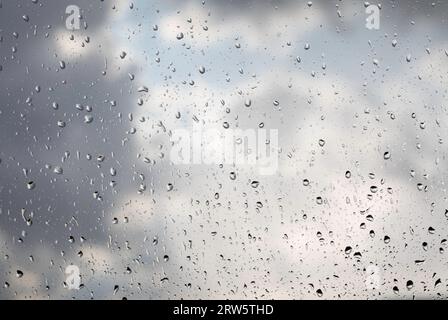 Water, rain drops on the window pane, glass. Lights of the city. Bokeh - abstract background. Stock Photo