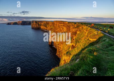 Cliffs of Moher, hiking woman watching the sunset, The Burren, County Clare, Ireland, United Kingdom The Burren, County Clare, Ireland, United Kingdom Stock Photo